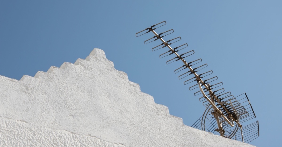 TV antenna on a white rooftop under a clear blue sky