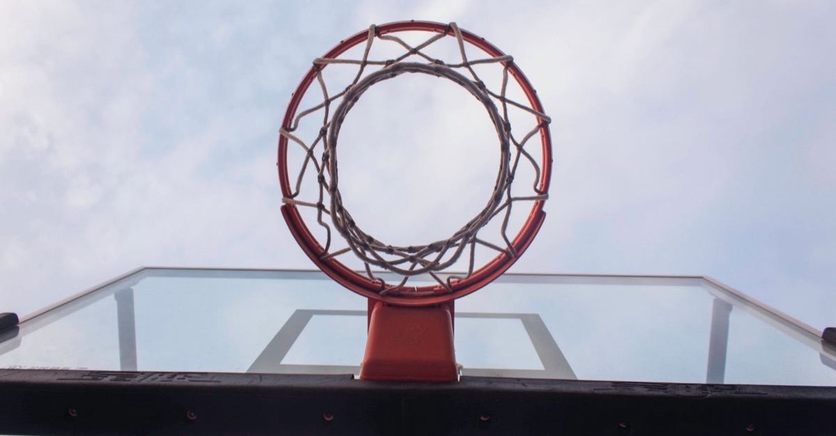 Basketball rim and net seen from below against a cloudy sky