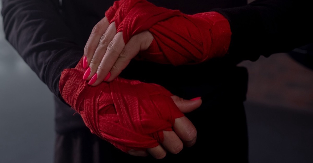 Close-up of hands being wrapped in red hand wraps before training