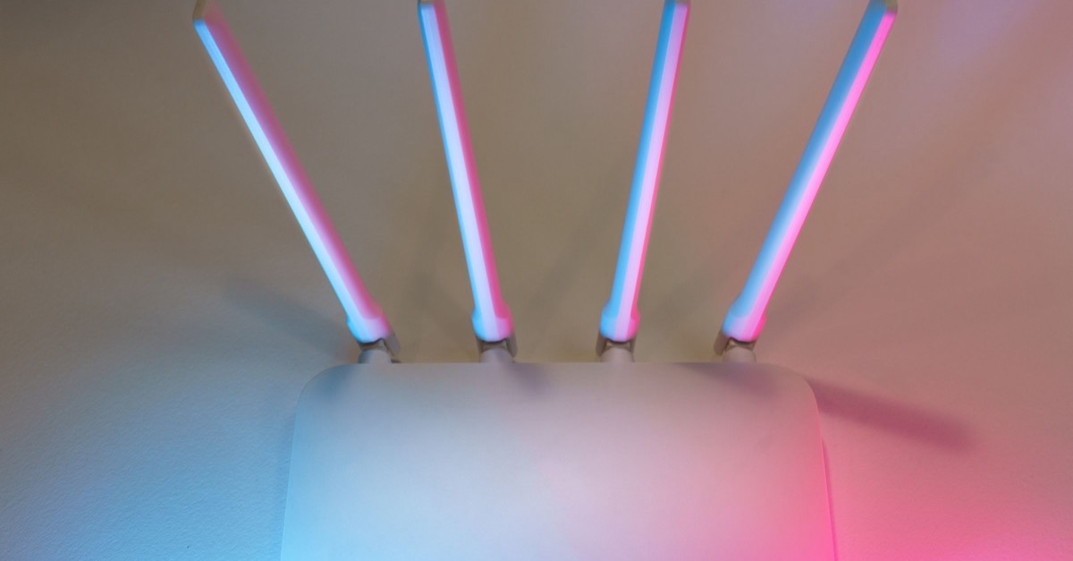 White wireless router with four antennas lit in blue and pink